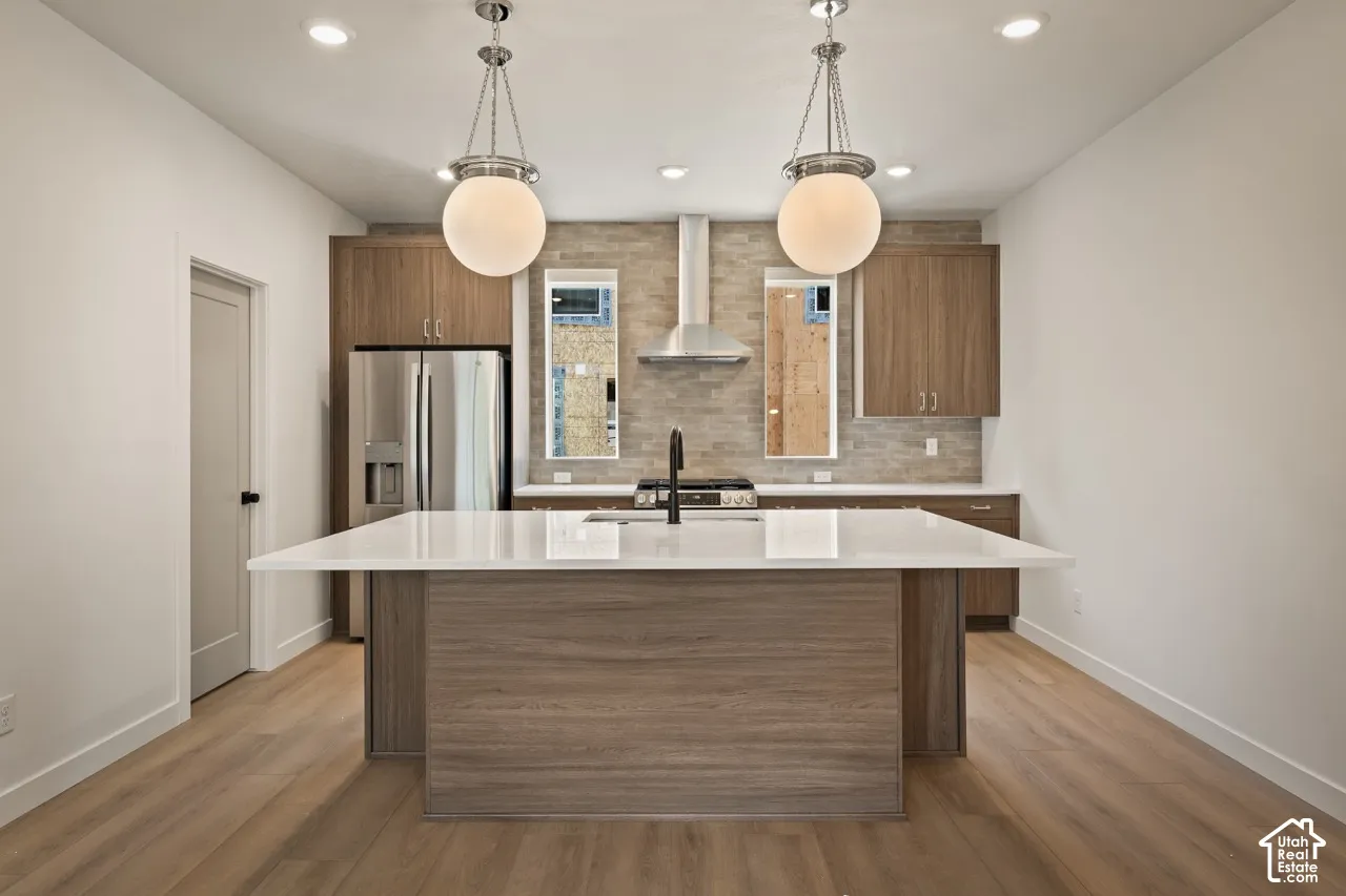 Kitchen featuring a large island with white countertop, stainless steel appliances, wood-finish cabinetry, and pendant lighting