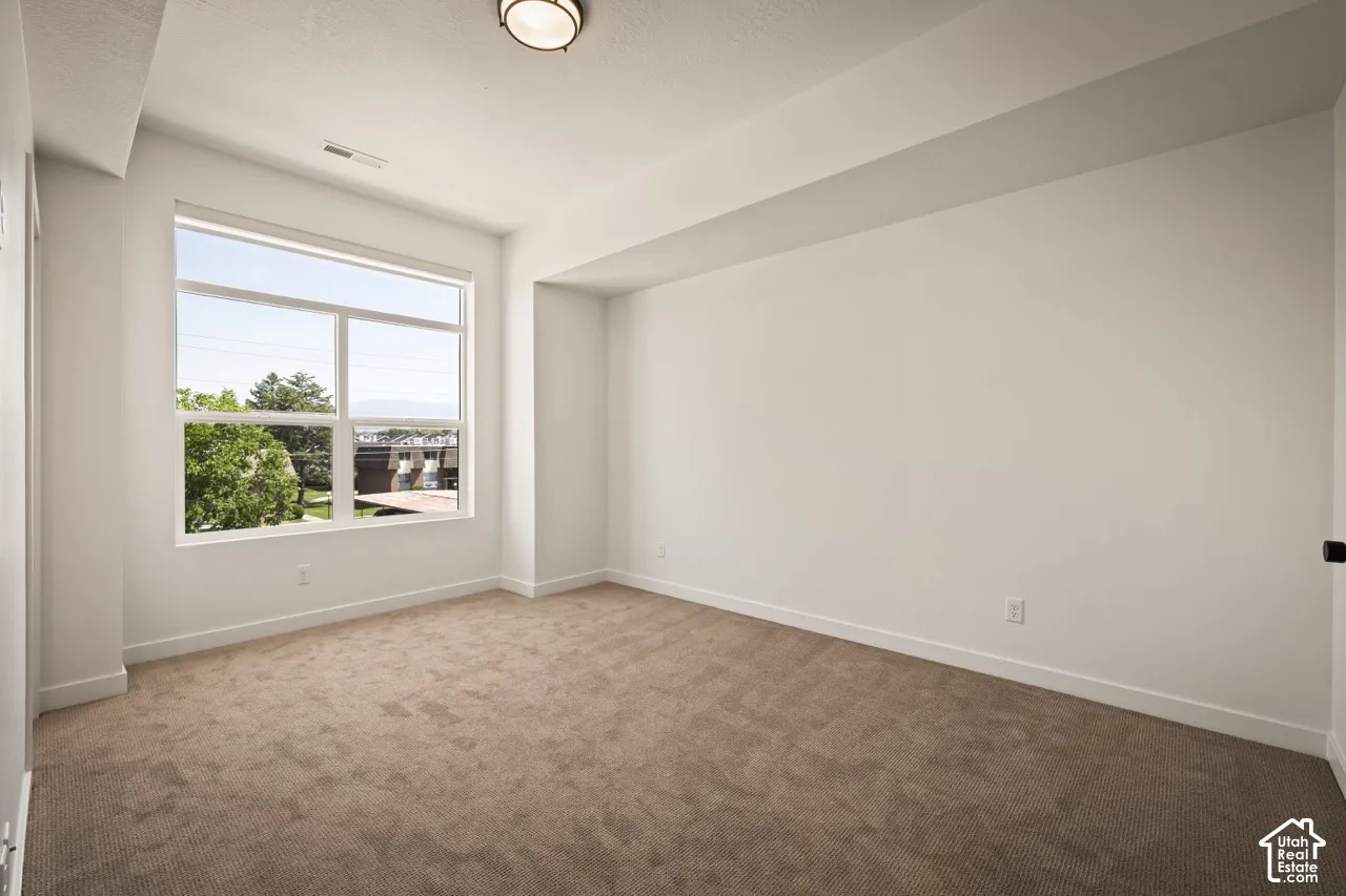 Recessed ceiling light fixture, large picture window, neutral carpeting, and white walls