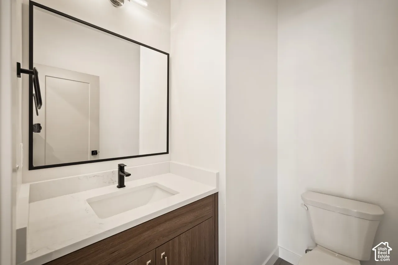 Sleek vanity featuring a wood-finish cabinet, integrated rectangular sink, and stone-look countertop