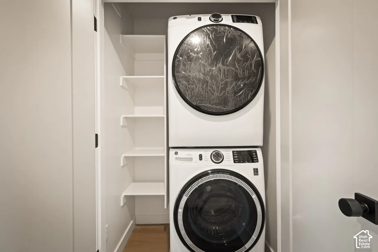 Stackable laundry appliances with a front-load washer and dryer, complemented by built-in shelving and light wood-finish flooring