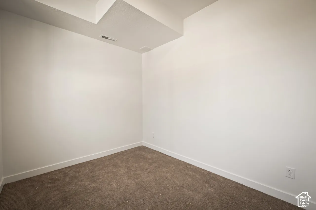 Neutral wall color, carpeted flooring, and a ceiling with multiple levels