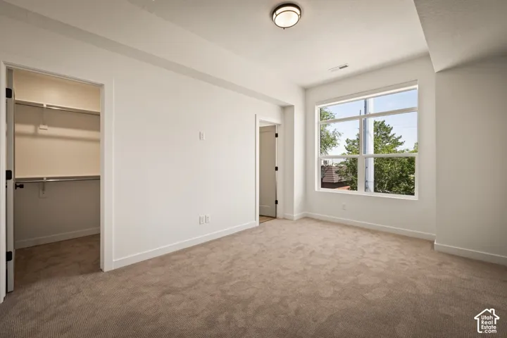 Neutral carpeting, white painted walls, and a large multi-pane window