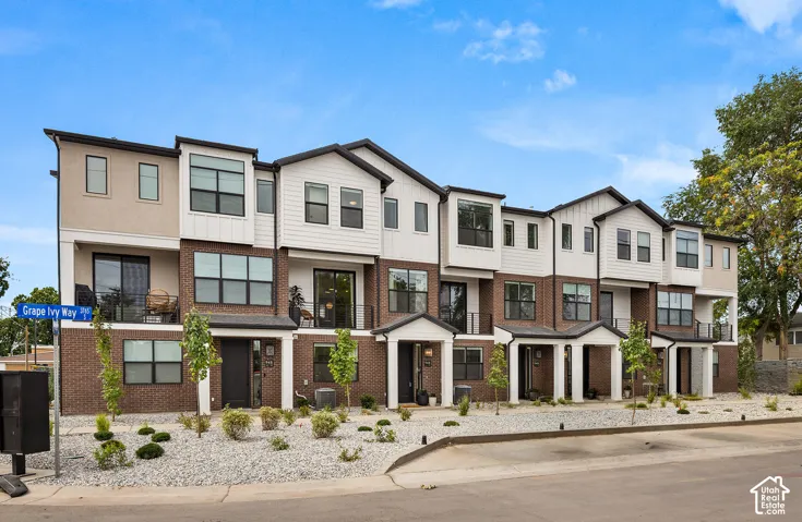 Modern townhomes featuring brick and horizontal siding exteriors, private balconies, covered entryways, and xeriscaped front areas