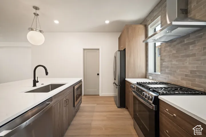 Modern kitchen featuring wood-finish cabinetry, stainless steel appliances, white countertops, and a tiled backsplash
