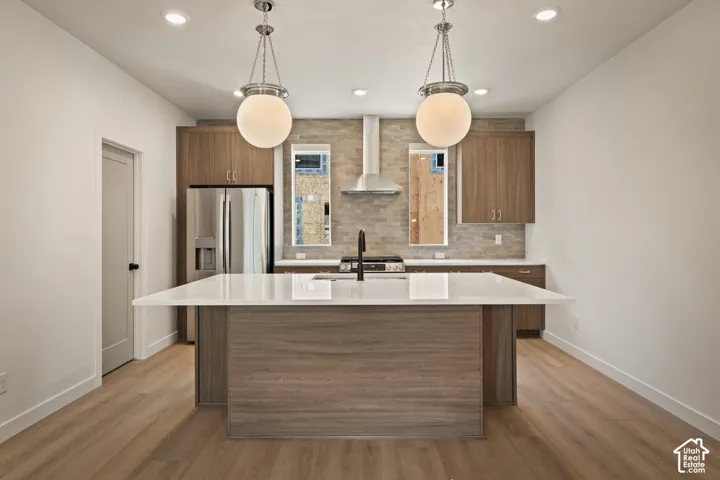Kitchen featuring a large island with white countertop, stainless steel appliances, wood-finish cabinetry, and pendant lighting