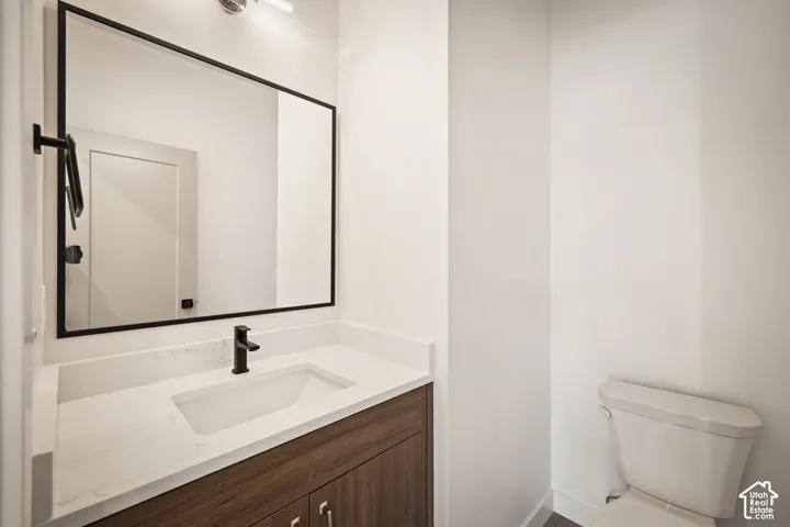 Sleek vanity featuring a wood-finish cabinet, integrated rectangular sink, and stone-look countertop