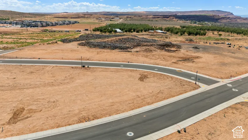 Expansive undeveloped lot with street access, paved roads, and distant mesa landscape