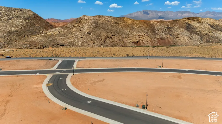 Paved roads with concrete curbing and utility infrastructure in place, set against a desert landscape with distant mountains