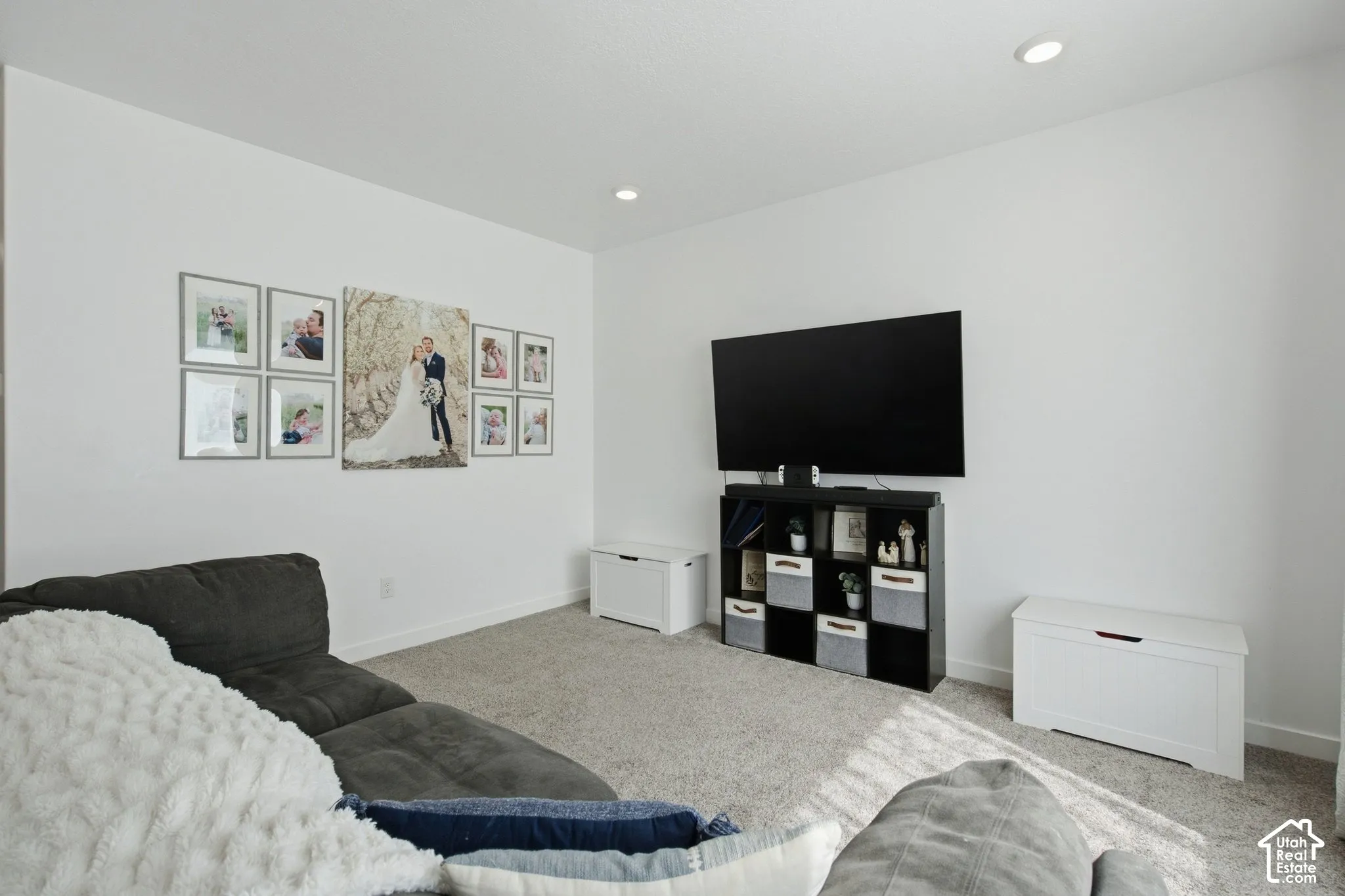 Recessed lighting illuminates the space, featuring neutral carpeting and white wall finishes