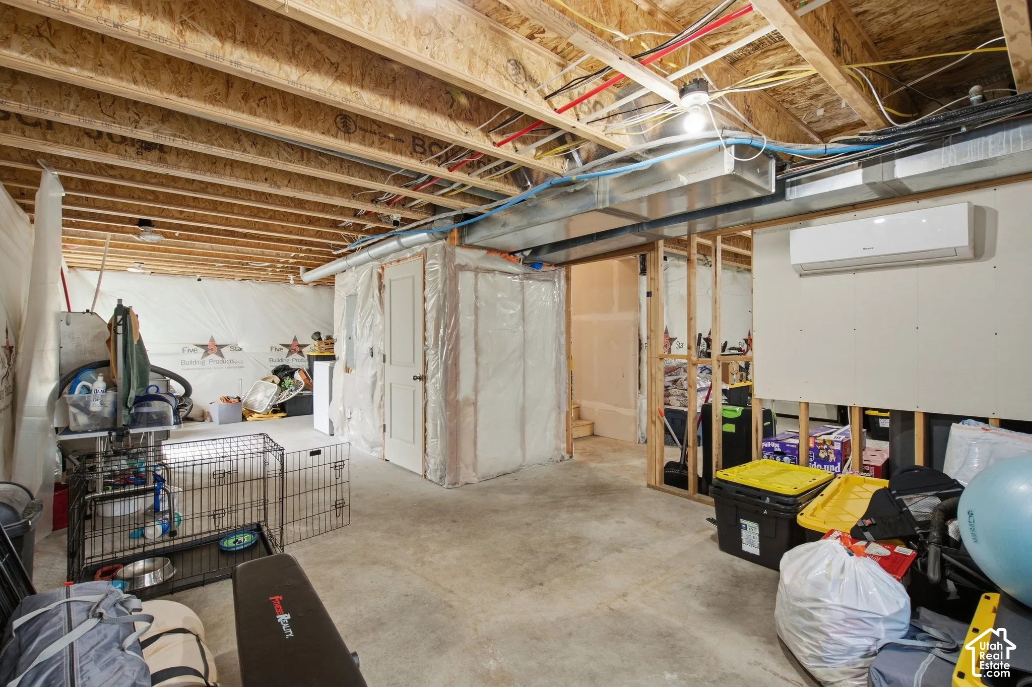 Unfinished lower level with exposed ceiling joists and concrete flooring