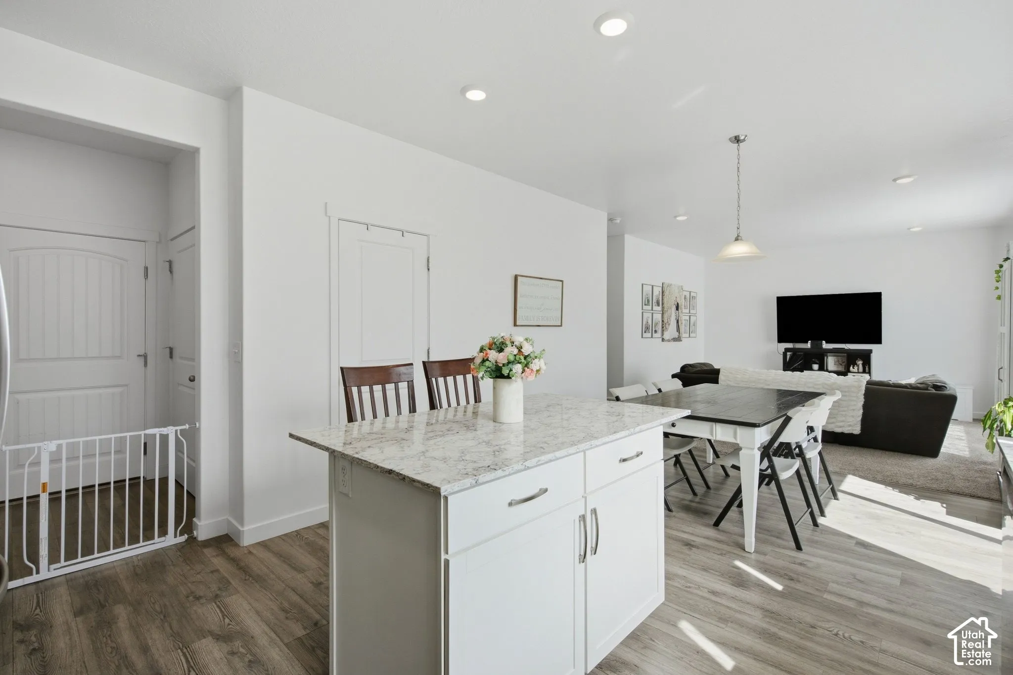 Kitchen island with a light-toned countertop, white cabinetry with silver hardware, and wood-finish flooring