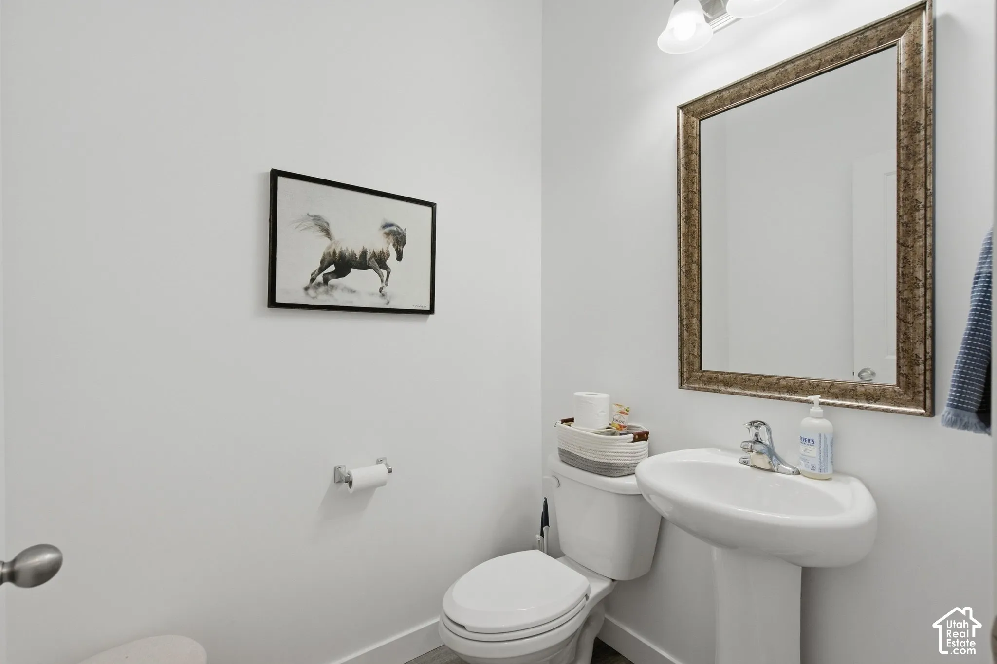 Pedestal sink with chrome faucet, framed mirror, and overhead vanity lighting