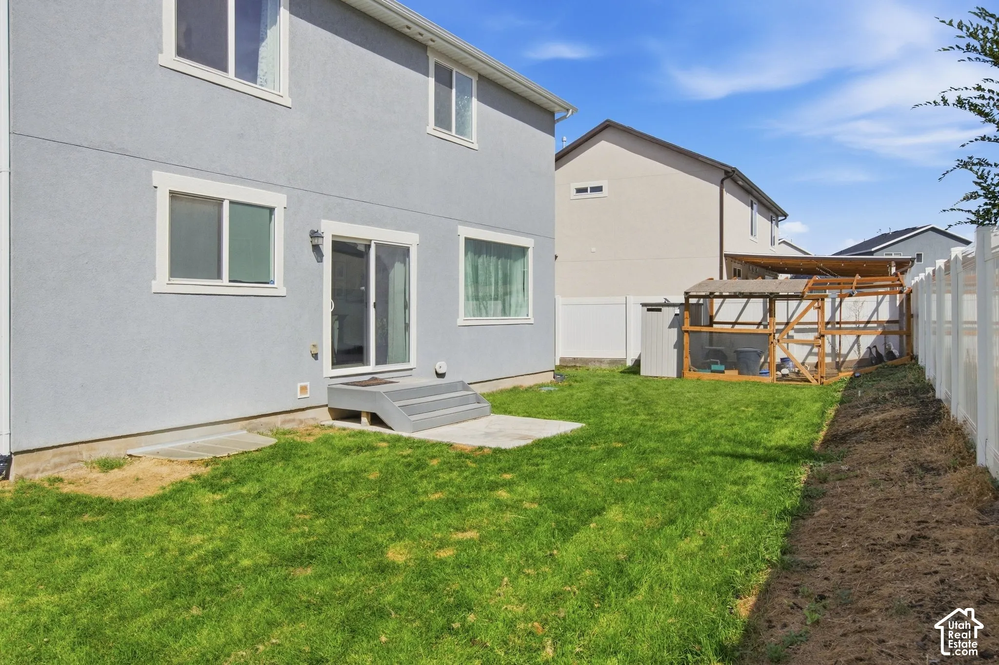 Rear exterior with a patio, sliding glass door, and a grass lawn