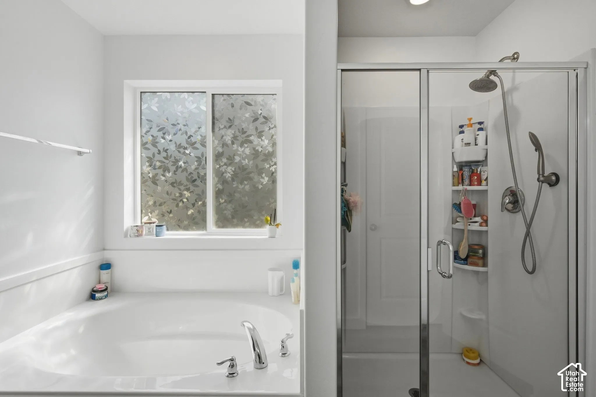 Soaking tub with deck-mounted chrome fixtures, adjacent to a glass-enclosed shower with a handheld spray and overhead showerhead
