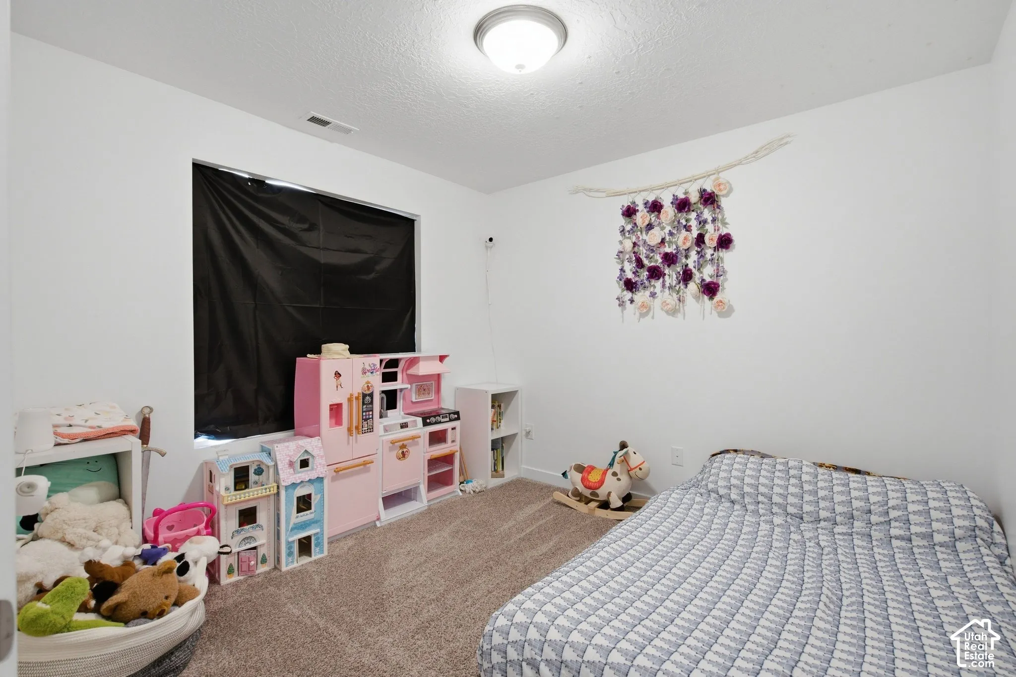 Carpeted room with a ceiling-mounted light fixture, white walls, and a window