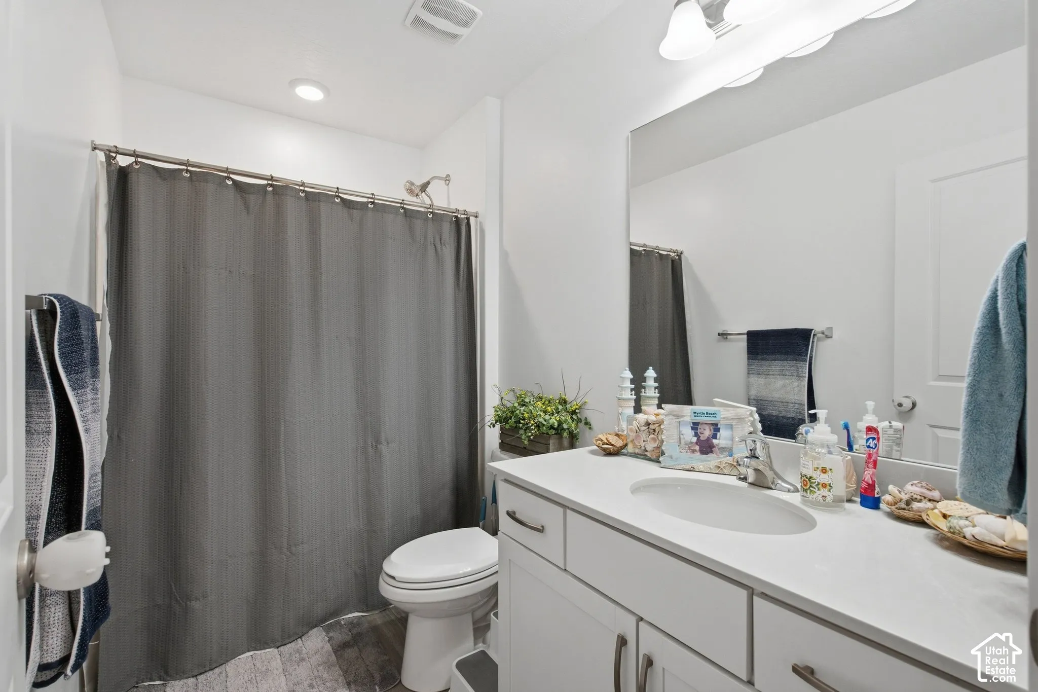 White single vanity with undermount sink, overhead lighting, and wall-mounted mirror