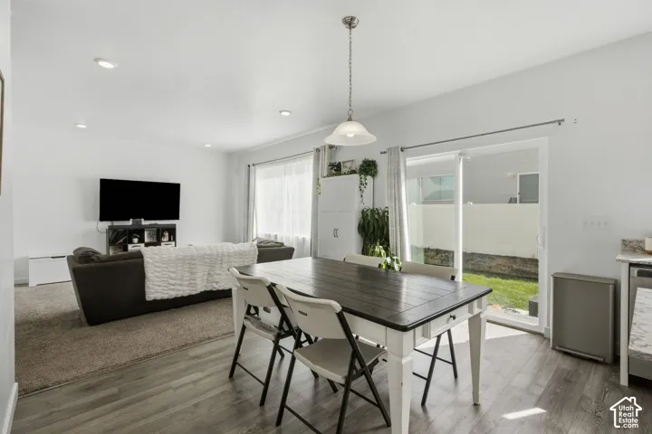 Wood-finish flooring, recessed lighting, pendant light fixture, sliding glass door, and backyard with green space