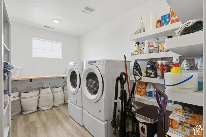Laundry room featuring a light wood-finish floor, white walls, and a window