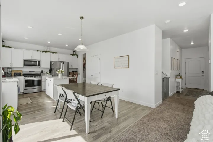 Open-concept kitchen with white cabinetry and stainless steel appliances