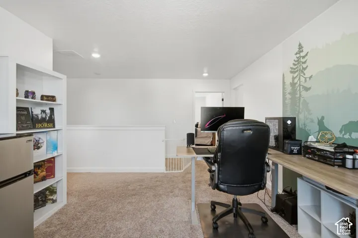 Carpeted space featuring a white built-in bookshelf, recessed lighting, and a painted accent wall