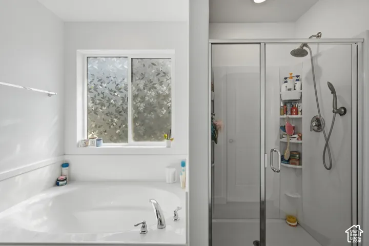 Soaking tub with deck-mounted chrome fixtures, adjacent to a glass-enclosed shower with a handheld spray and overhead showerhead