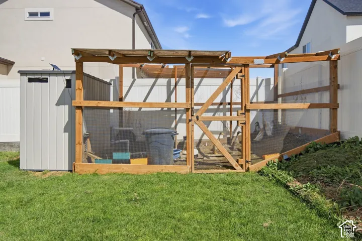 Expansive yard featuring a wooden animal enclosure, a gray storage shed, and a privacy fence
