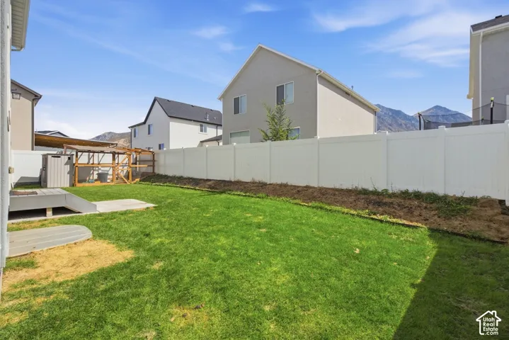 Expansive backyard featuring a manicured lawn, a full white privacy fence, and a built-in outdoor structure