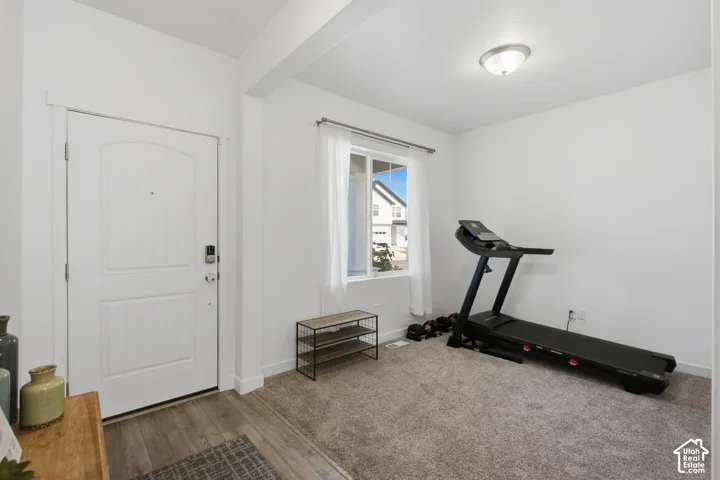 Entryway featuring a white paneled door with smart lock, wood-finish flooring, and a carpeted area with a window