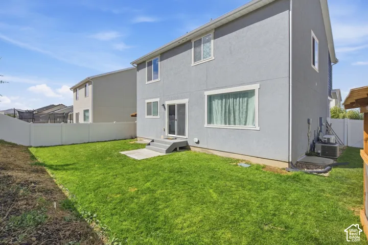 Fenced backyard with a concrete patio, green lawn, and stucco exterior
