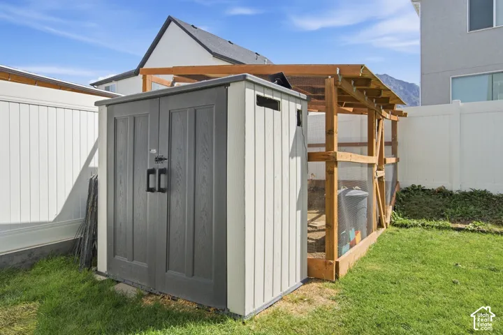 Plastic storage shed with double doors, wood-framed enclosure, and privacy fencing