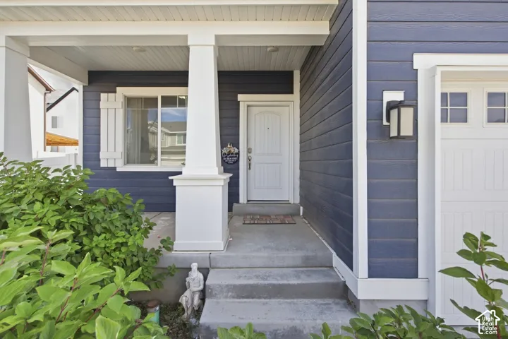 Covered porch entry featuring white columns, a paneled front door, and a built-in outdoor light fixture