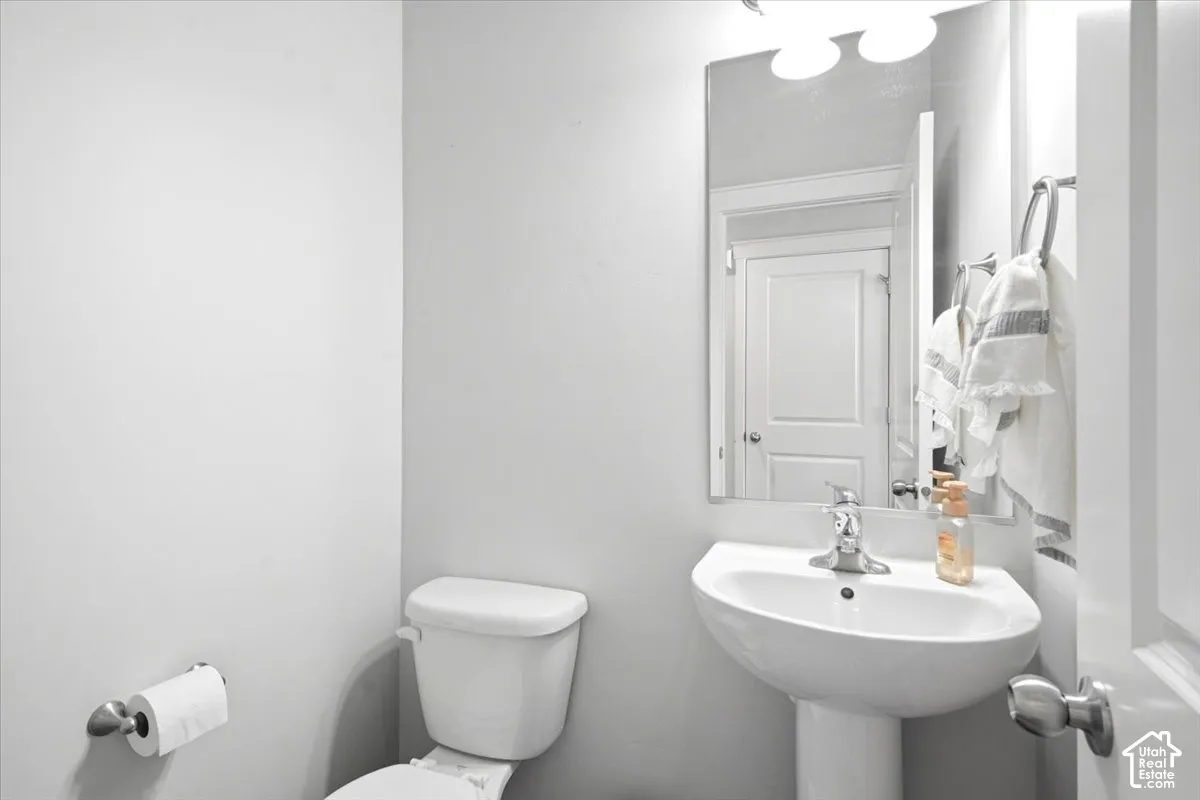 Pedestal sink with chrome faucet, full-width wall mirror, and overhead vanity lighting