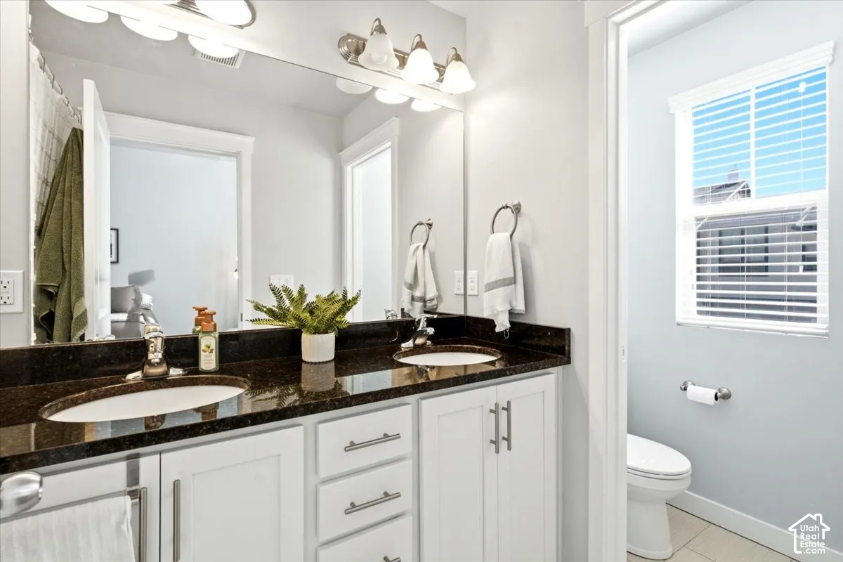 Dual vanity with dark countertop, undermount sinks, and white cabinetry
