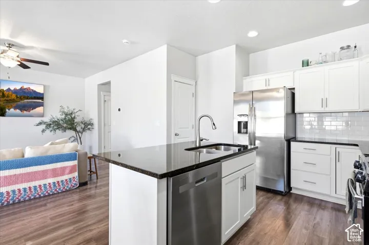 Kitchen featuring white cabinetry, dark countertops, stainless steel appliances, and a subway tile backsplash