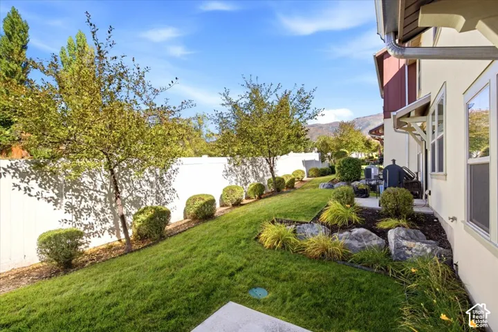 Expansive lawn area, white privacy fence, established trees, decorative shrubs, and a rock garden
