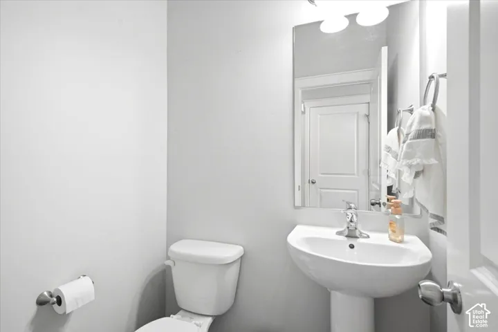 Pedestal sink with chrome faucet, full-width wall mirror, and overhead vanity lighting