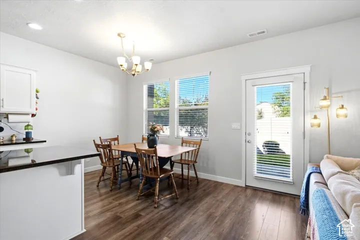 Wood-finish flooring throughout, white cabinetry with dark countertops, and a glass-paneled exterior door