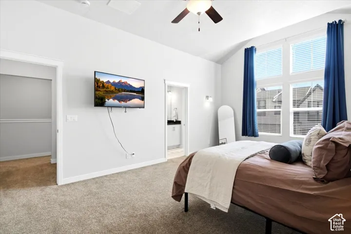 Vaulted ceiling, ceiling fan, wall-mounted television, large windows, and carpet flooring