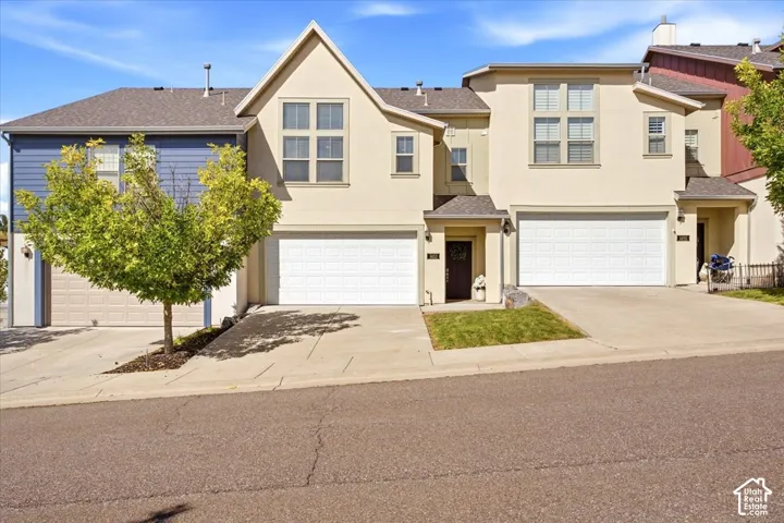 Multi-level stucco facade, attached garage, covered entry, front landscaping, and a pitched roof