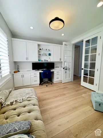 White built-in cabinetry with open shelving, wood-finish flooring, recessed lighting, and French doors
