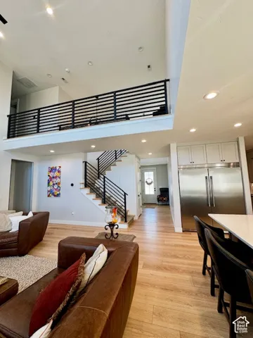 Loft area featuring a contemporary horizontal railing, recessed lighting, wood-finish flooring, a stainless steel refrigerator, and white cabinetry