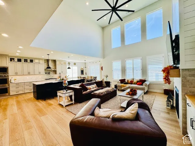 Soaring vaulted ceiling with a modern ceiling fan, wood-finish flooring, and a stone-clad fireplace