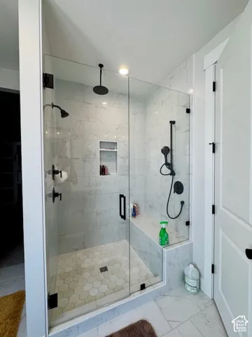 Spacious walk-in shower with clear glass enclosure and matte black fixtures