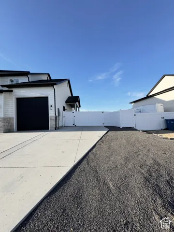 White-sided residence with a black garage door and a concrete driveway