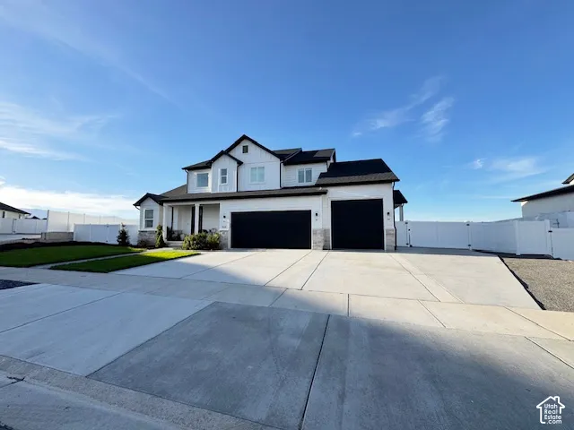 Contemporary exterior with white siding and black accents, featuring a two-car garage, a covered front porch, and a concrete driveway