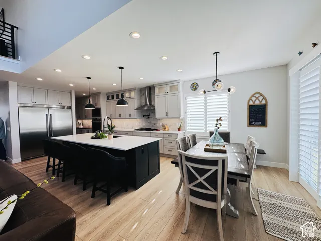 Spacious open-concept living area featuring light wood-finish flooring, a kitchen island with a white countertop, stainless steel appliances, white cabinetry, and recessed lighting