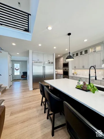 Kitchen featuring light-toned wood-finish flooring, white countertops, gray cabinetry, stainless steel appliances, and recessed lighting
