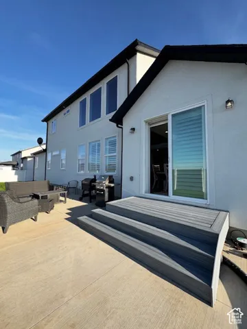 Exterior featuring a stucco finish, multi-pane windows, a sliding glass door, and a composite deck with integrated steps