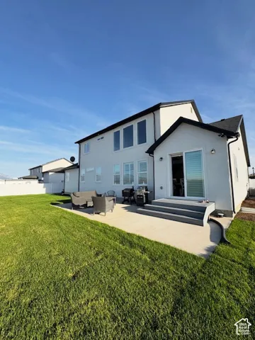 Expansive green lawn with a concrete patio, exterior steps, and a sliding glass door