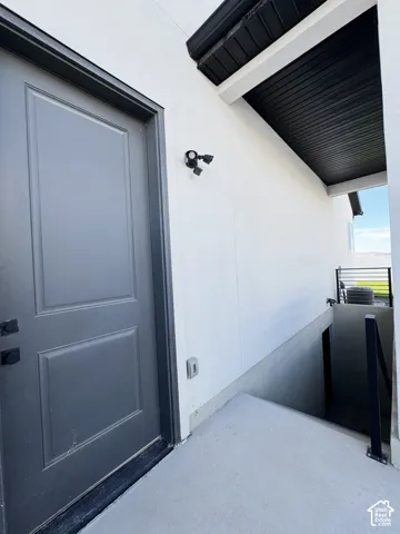 Recessed paneled entry door, exterior wall-mounted fixture, and concrete walkway